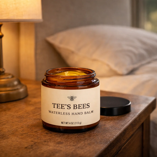 Tee's Bees waterless hand balm jar on a wooden surface with a blurred background